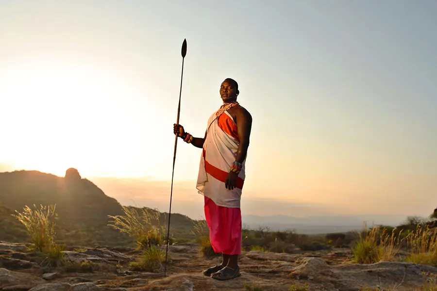 Un miembro de la tribu samburu se yergue con las pintorescas montañas de Kalama Conservancy a sus espaldas al amanecer.