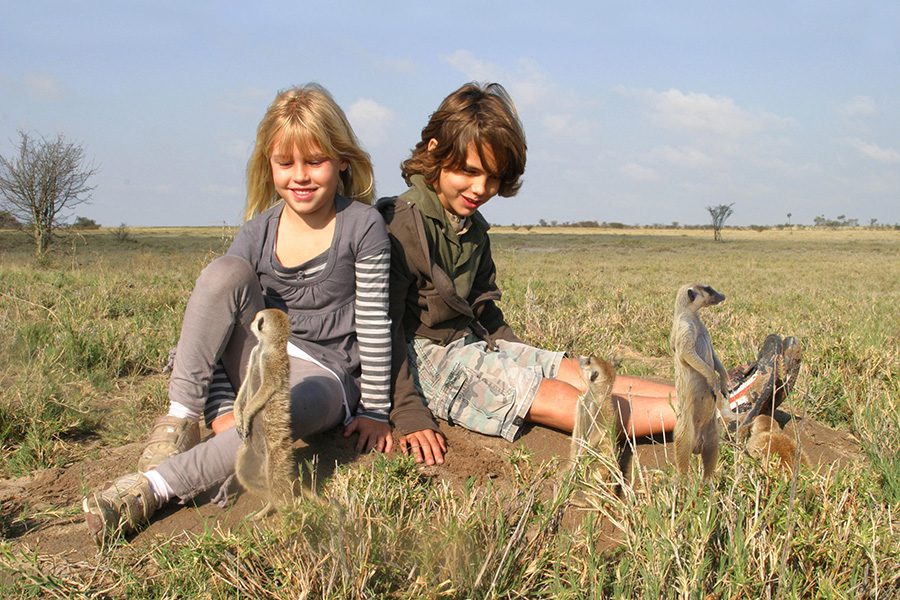 Children interact with meerkats at Jack's Camp in Botswana.