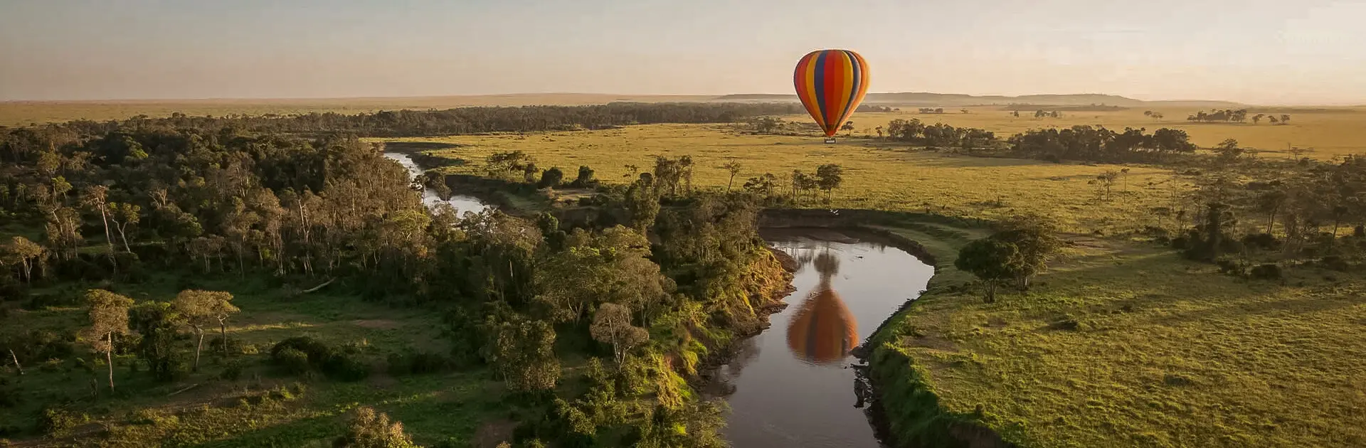 A hot air balloon hovers over a meander in the river | Go2Africa