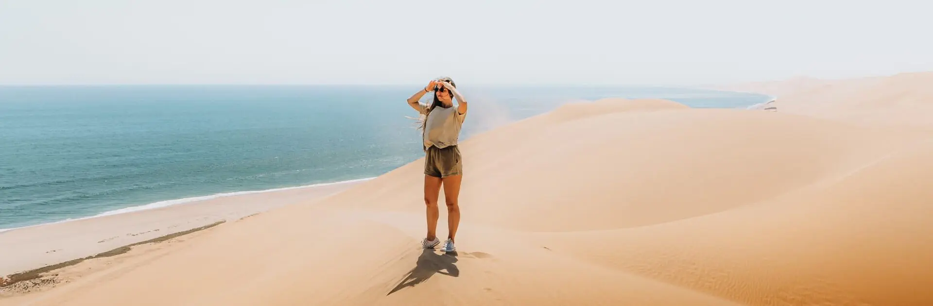 Young woman traveling in Namibia, walking at the big dunes meeting the ocean at Namib-Naukluft National Park, Namibia | Go2Africa