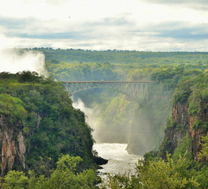 Hear the thunderous sounds of the water rushing below the Victoria Falls Bridge and the spray of the Falls.
