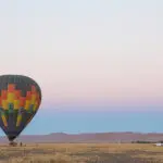 Unas montañas lejanas se tiñen de rosa durante un vuelo en globo al amanecer en Namibia.