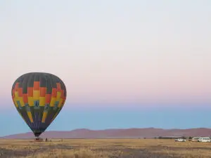 Bergen in de verte gloeien roze op tijdens een ballonvaart bij zonsopgang in Namibië.