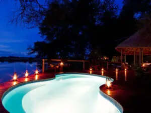 Una romántica iluminación enmarca la piscina del Kwando Lagoon Camp, situado en una de las reservas privadas más exclusivas de Botsuana.