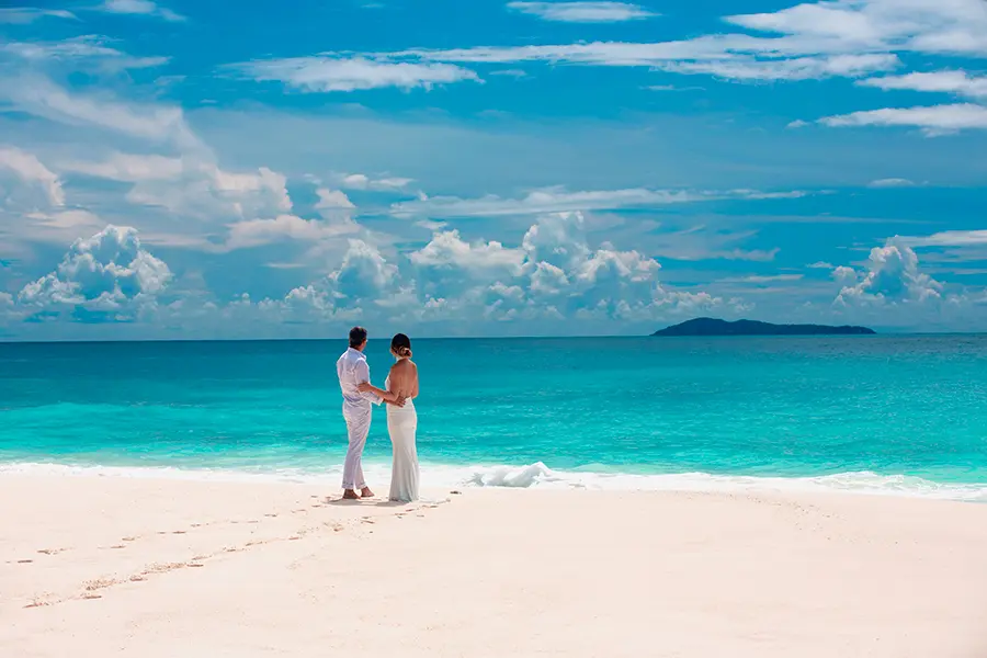A couple stand on a beautiful, white beach on Cousine Island | Go2Africa