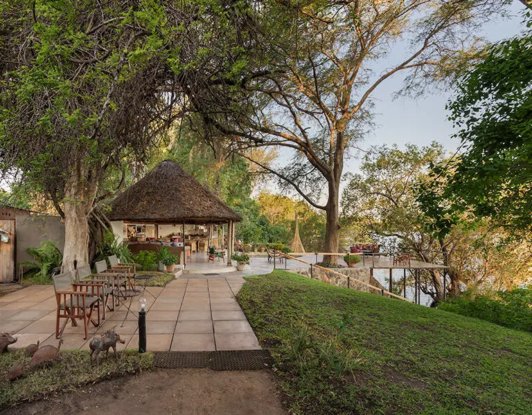 Chundukwa's peaceful riverside setting, shaded by tall trees.