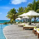 Comfortable sun loungers line the swimming pool looking out to the azure sea. 