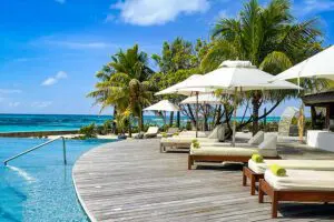 Comfortable sun loungers line the swimming pool looking out to the azure sea. 