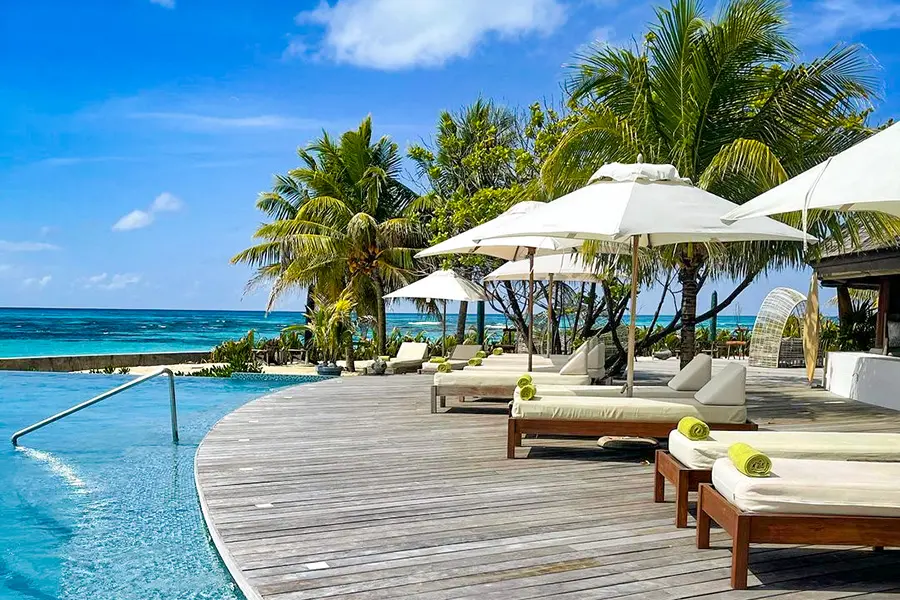 Comfortable sun loungers line the swimming pool looking out to the azure sea. 