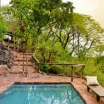 El lodge es lujoso y rústico a la vez, con caminos de piedra que conducen a las suites y la piscina.