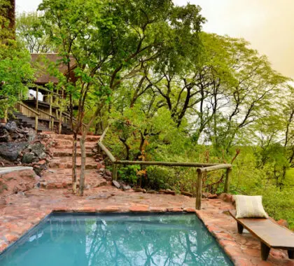 El lodge es lujoso y rústico a la vez, con caminos de piedra que conducen a las suites y la piscina.