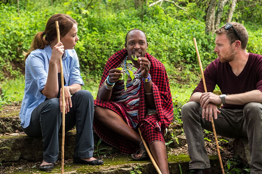 Dos huéspedes sentados con su guía local en una excursión por las plantaciones de la Granja Gibbs en Tanzania | Go2Africa