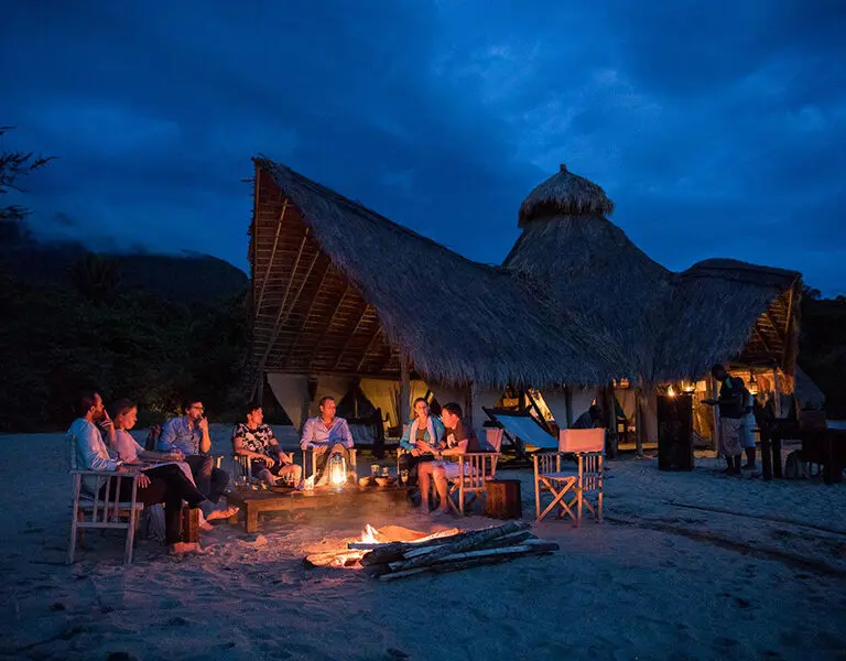 Tauschen Sie bei einem Sundowner am Feuer am Strand Geschichten über die Ereignisse des Tages aus.