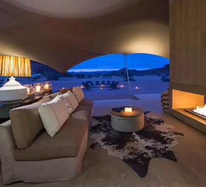 Un acogedor sofá junto a la chimenea ofrece un ambiente familiar a este campamento remoto y absolutamente único.