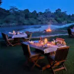 Cena bajo las estrellas con la hoguera crepitando cerca y los hipopótamos revolcándose en el río.