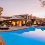 Relájese en la zona de estar exterior bajo la elegante carpa durante el calor del día con una bebida refrescante y una piscina chispeante.