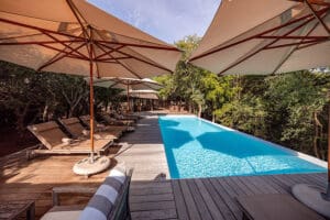  La zona de la piscina está protegida por un frondoso follaje y se completa con tumbonas.