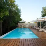  The swimming pool area is protected by lush foliage and completed with sun loungers.