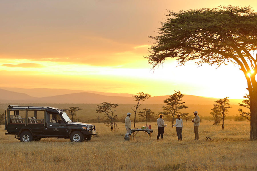 A safari vehicle and several people having sundowners on safari | Go2Africa