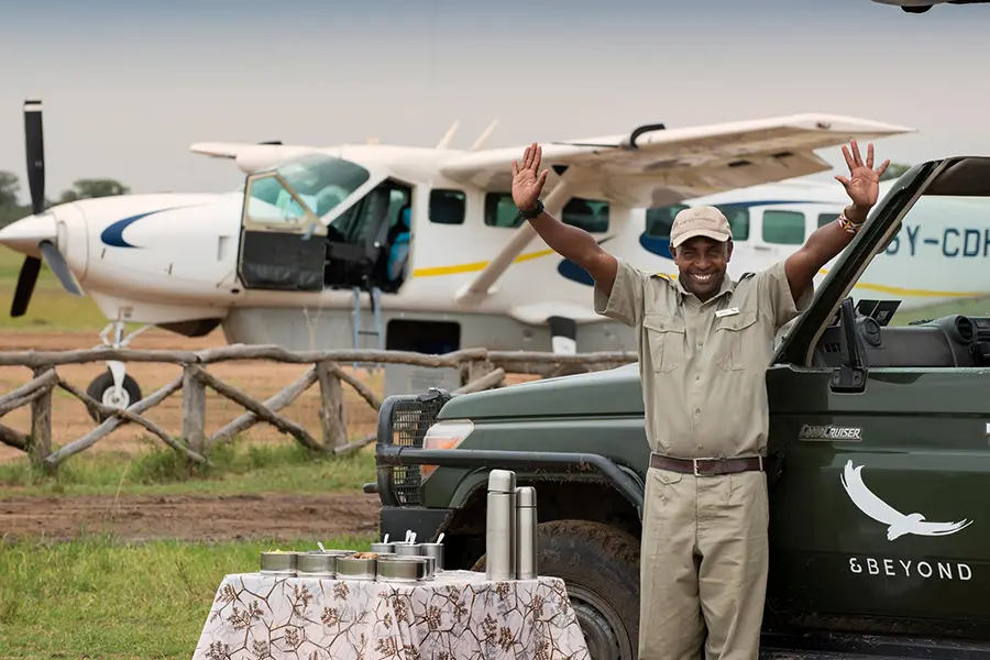 Un avión aterriza en una pista cercana a AndBeyond Kichwa Tembo, donde el personal kichwa espera alegremente a los huéspedes con un vehículo de safari 4x4.