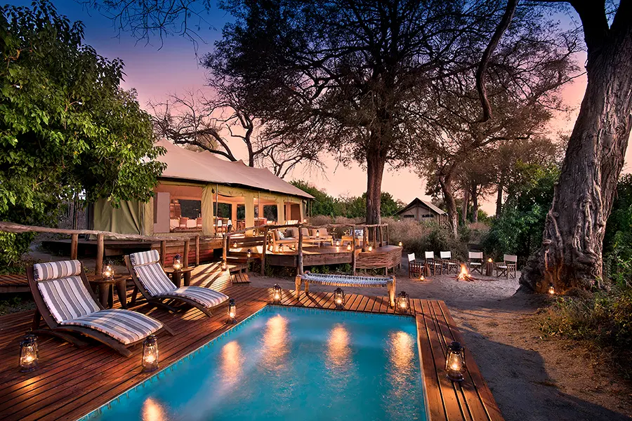 Looking up at Linyanti Ebony from the pool lit by lanterns at sunset | Go2Africa