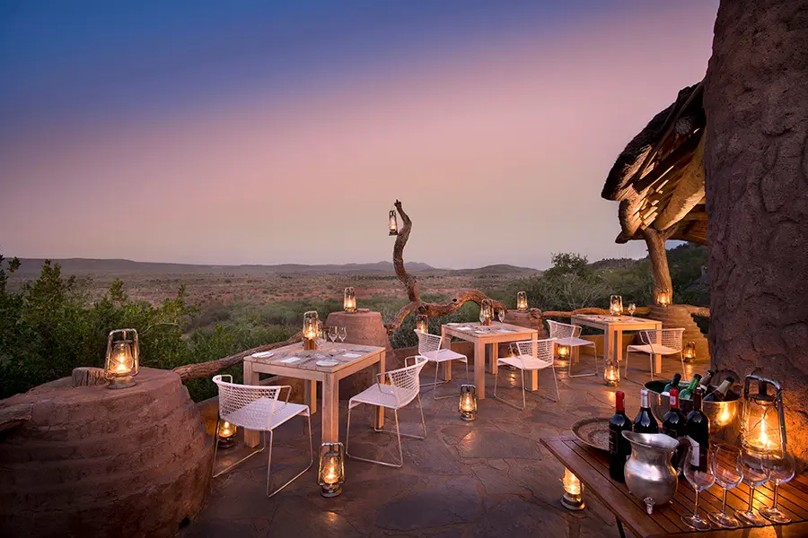 Varias mesas con románticas linternas dan a la Reserva de Caza Madikwe al atardecer | Go2Africa