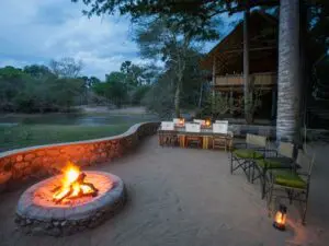 Tras disfrutar de una copa alrededor de la hoguera al aire libre, deguste una cena recién preparada a la luz de los faroles.