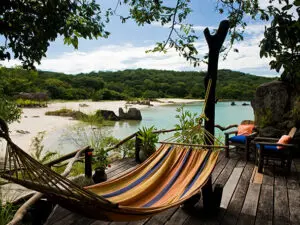 Una terraza de madera con hamaca y vistas a la playa: el lago Malawi es un paraíso tropical de playa en el corazón de África.