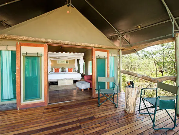 Unas puertas dobles comunican el interior de la suite con su terraza de madera a la sombra, equipada con tumbonas.