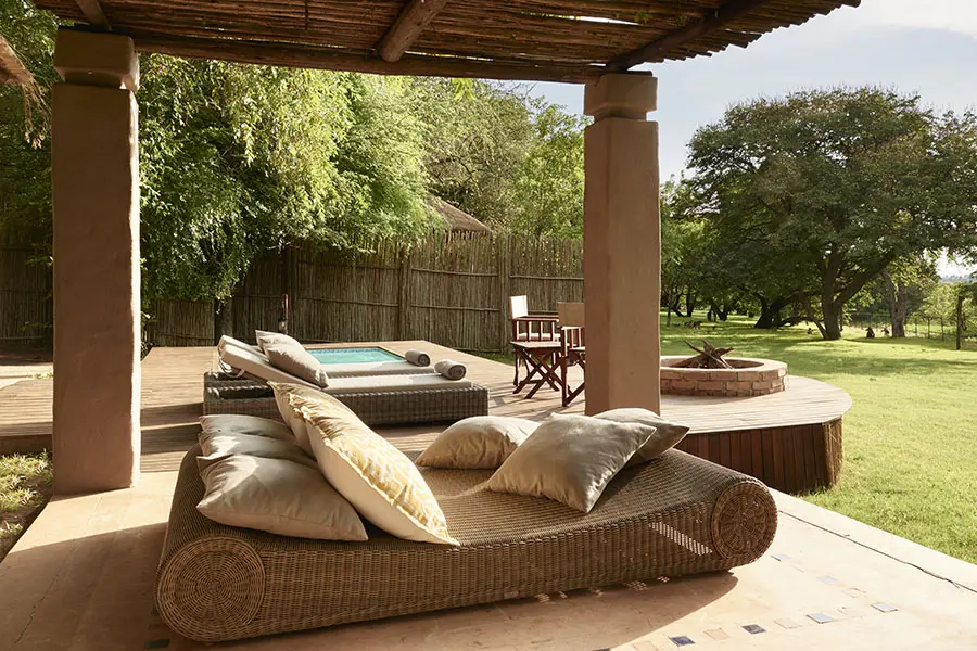 A plunge pool, fire pit, and sun loungers overlook lush greenery at Sanctuary Chobe Chilwero | Go2Africa