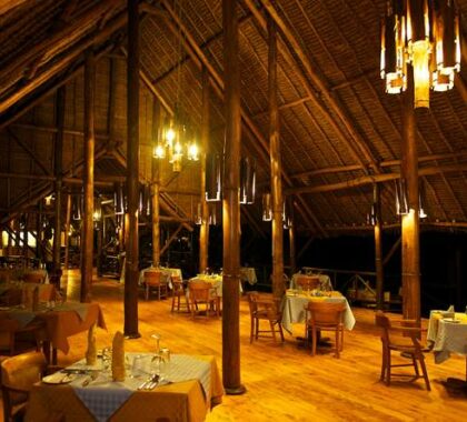 Raised off the ground to catch river breezes, the dining room sits under a grand, palm-thatched roof.