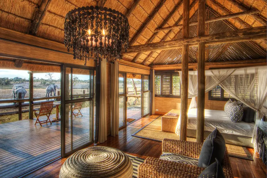 Una espaciosa habitación en el Savute Safari Lodge con vistas a un abrevadero con elefantes | Go2Africa