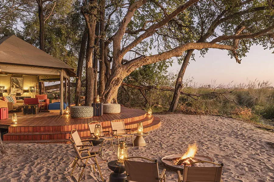 A small seating area surrounding a fire features in the foreground while several steps lead up to an open-air elevated sitting room both overlooking nature | Go2Africa