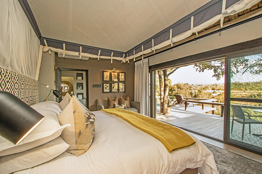 A tasteful suite at Simbambili Game Lodge features mustard yellow accents and a large deck overlooking the surrounding bush | Go2Africa