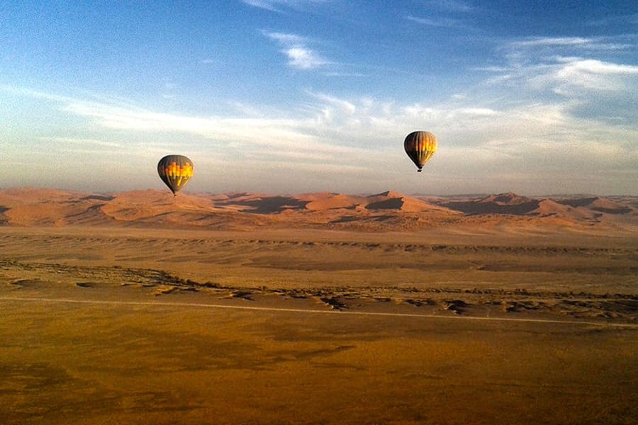 Two hot air balloons float above the Namibia desert and sand dunes with guests from Sossusvlei Lodge | Go2Africa