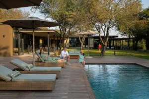 tanda-tula-safari-camp-exterior-guests-at-the-pool