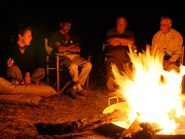 A comfortable chair & a campfire signal the time for tall drinks & even taller stories.