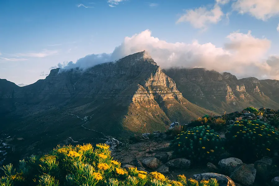 Vistas del Pico del Diablo de Table Mountain, nubes sobre la cima de la montaña mientras el sol brilla contra su cara.