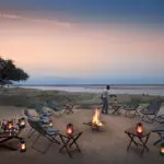 Saboree bebidas altas alrededor del fuego del boma mientras se maravilla con la espectacular vista del río Zambeze.