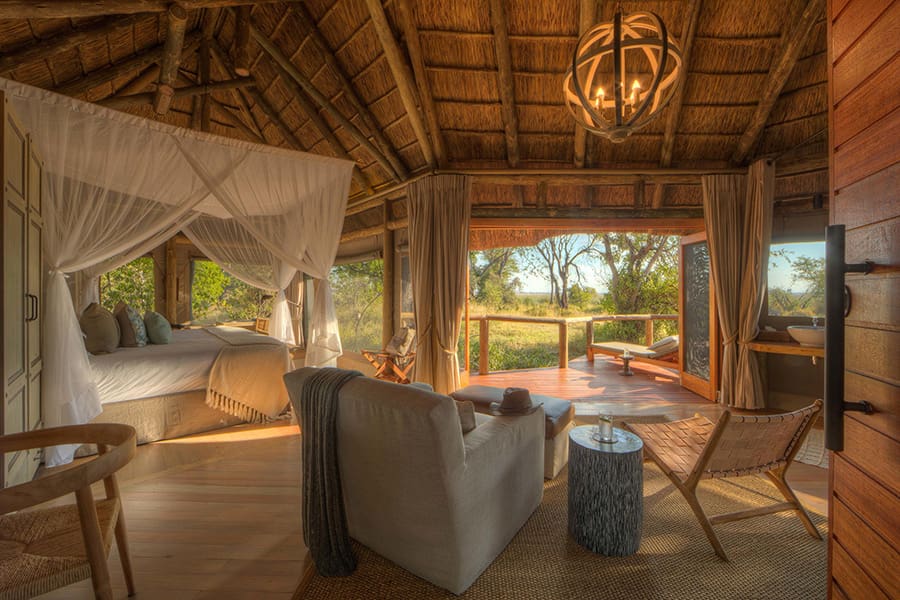 Un lujoso interior con cama con dosel y balcón con vistas a la sabana que rodea el Campamento Moremi | Go2Africa