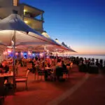 Empápese del ambiente en uno de los numerosos restaurantes y bares de la playa; una noche de verano es especialmente agradable.