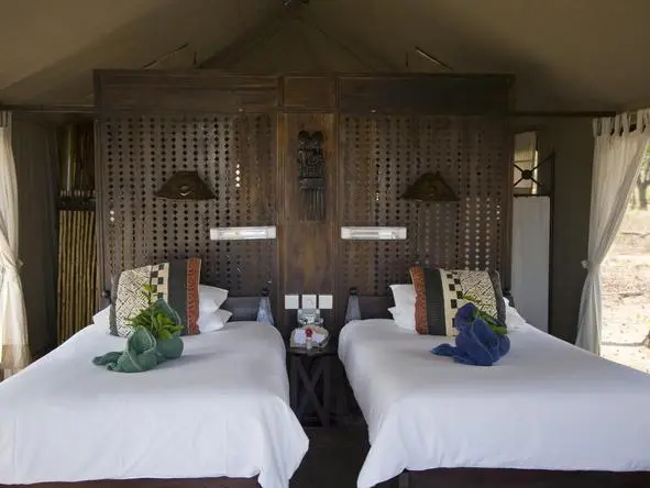Las cómodas habitaciones combinan ropa de cama blanca y madera oscura pulida.