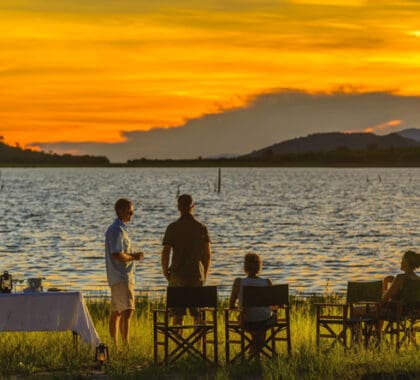 Los invitados se reúnen en la orilla para tomar una copa al atardecer.