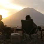 Siéntese y disfrute de una bebida al atardecer de su elección mientras la silueta del volcán Oldoinyo Lengai domina el horizonte.