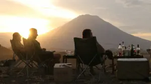 Siéntese y disfrute de una bebida al atardecer de su elección mientras la silueta del volcán Oldoinyo Lengai domina el horizonte.