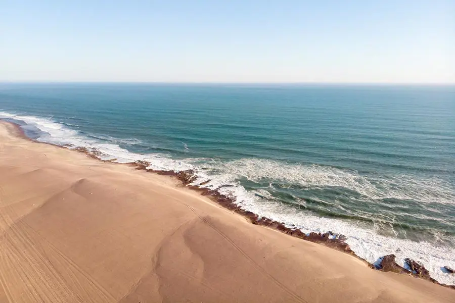 Contrasting landscapes on Namibia's Skeleton Coast with waves crashing on the beach | Go2Africa