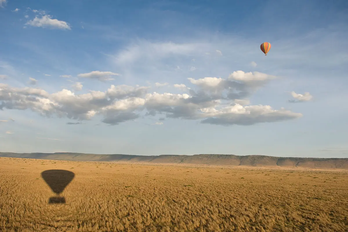 Safari on a hot air balloon casting a shadow on the Masai Mara, Kenya