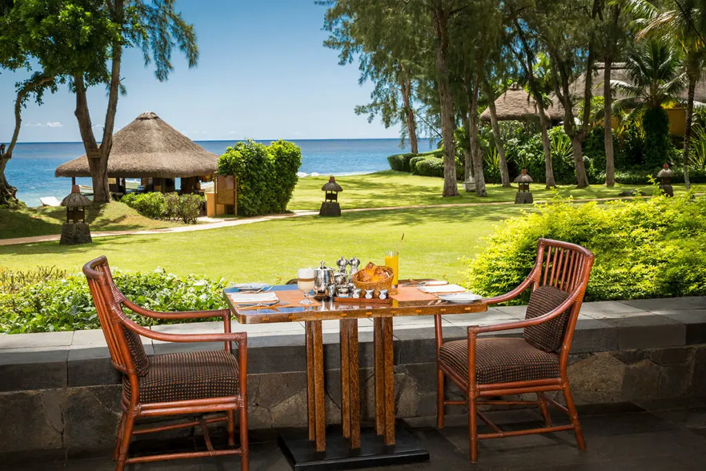 A table with two chairs overlooking the gardens and ocean at The Oberoi Beach Resort in Mauritius | Go2Africa