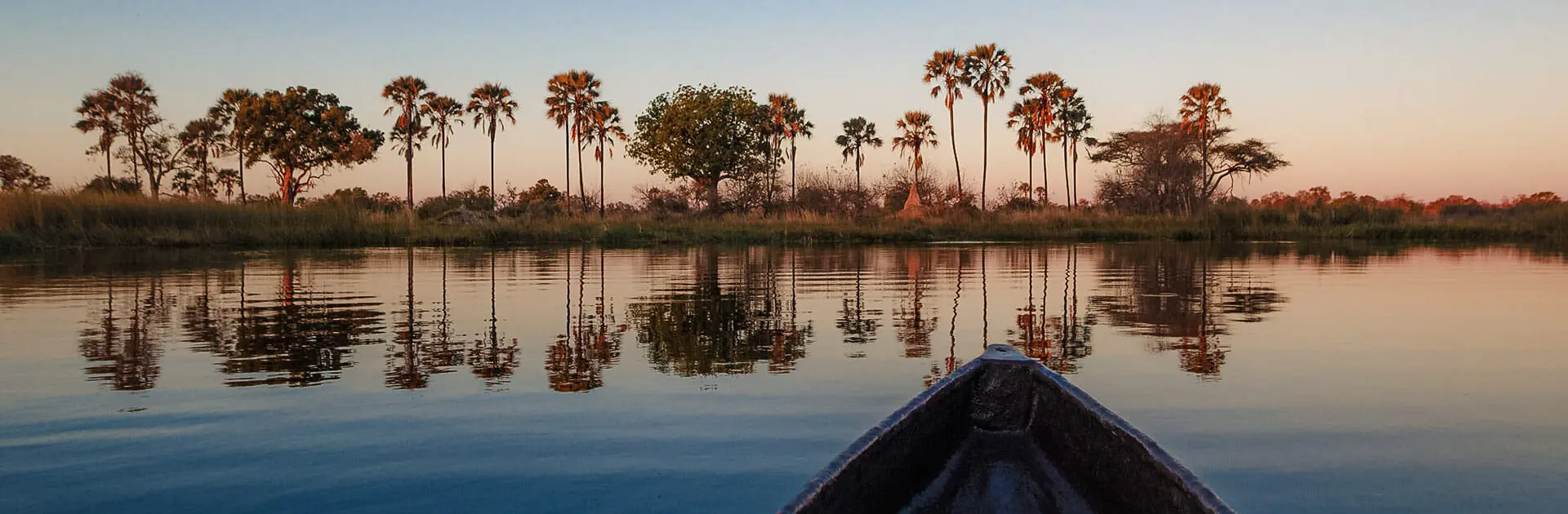 Explorando en un mokoro con árboles y tierra a lo lejos | Go2Africa