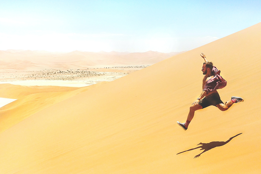 Man runs down the dunes of Sossusvlei in Namibia.